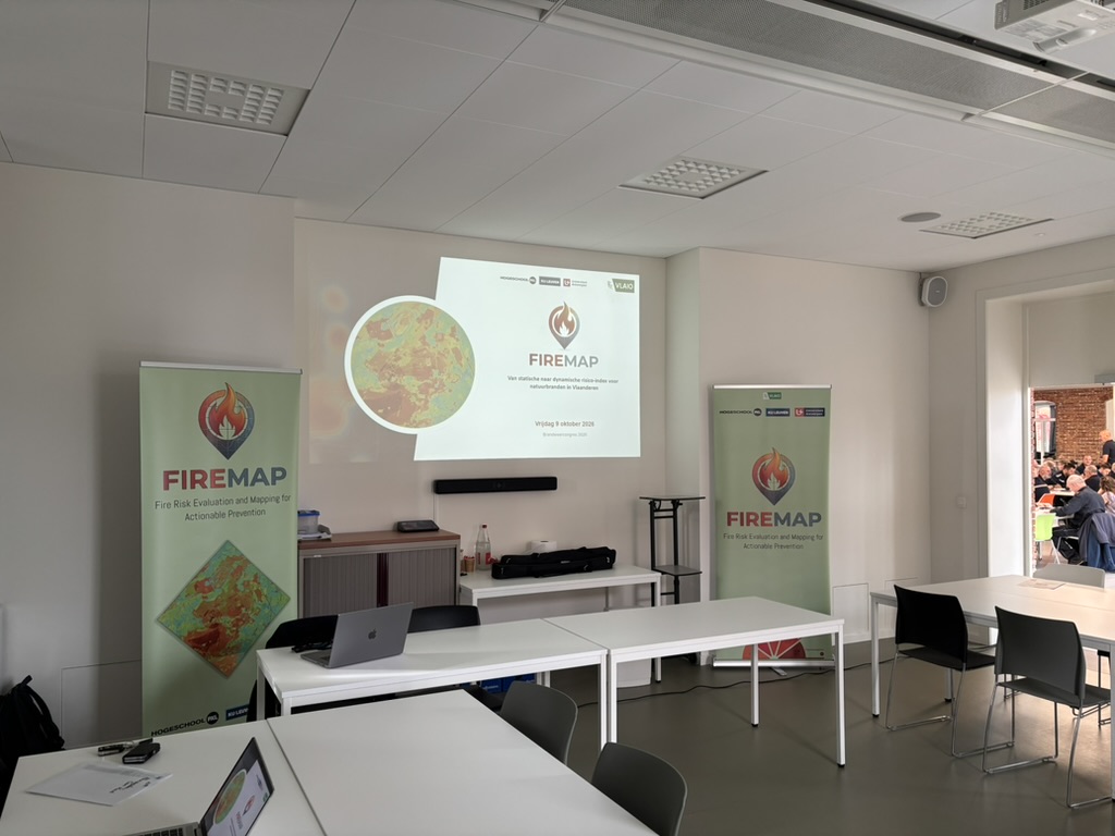 Zaal met FireMap-banners, met door de deur zicht op het drukke congres