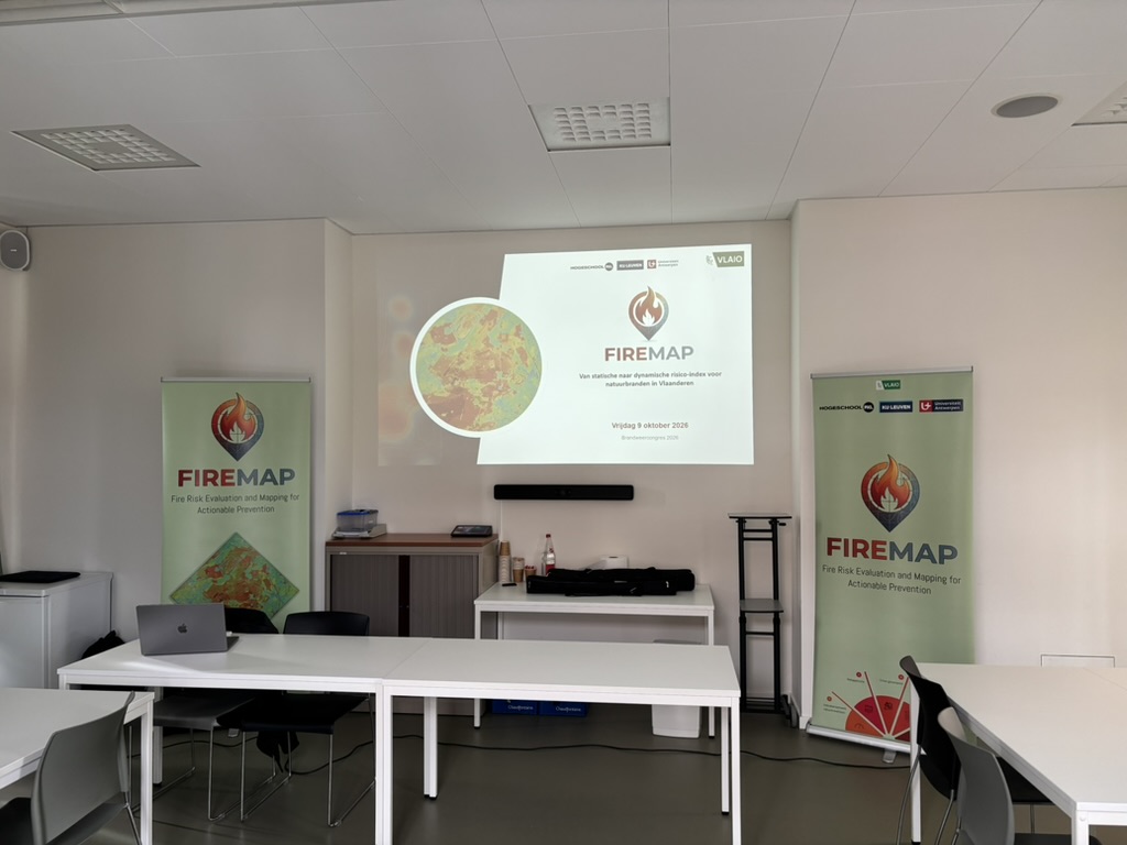 Zaal met FireMap-banners en de titelslide van de presentatie op het scherm