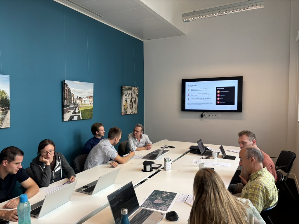 Een groep deelnemers bespreekt rond een tafel met kaarten en laptops het natuurbrandrisico van een site